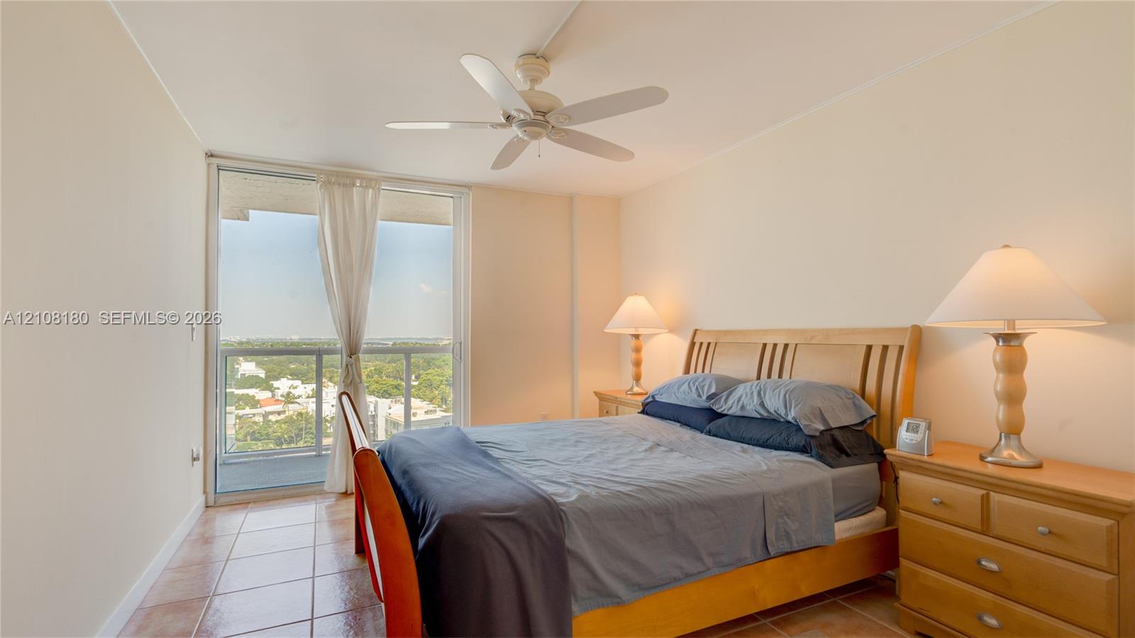 Room featuring tile flooring, a white ceiling fan, and sliding glass doors with a metal railing