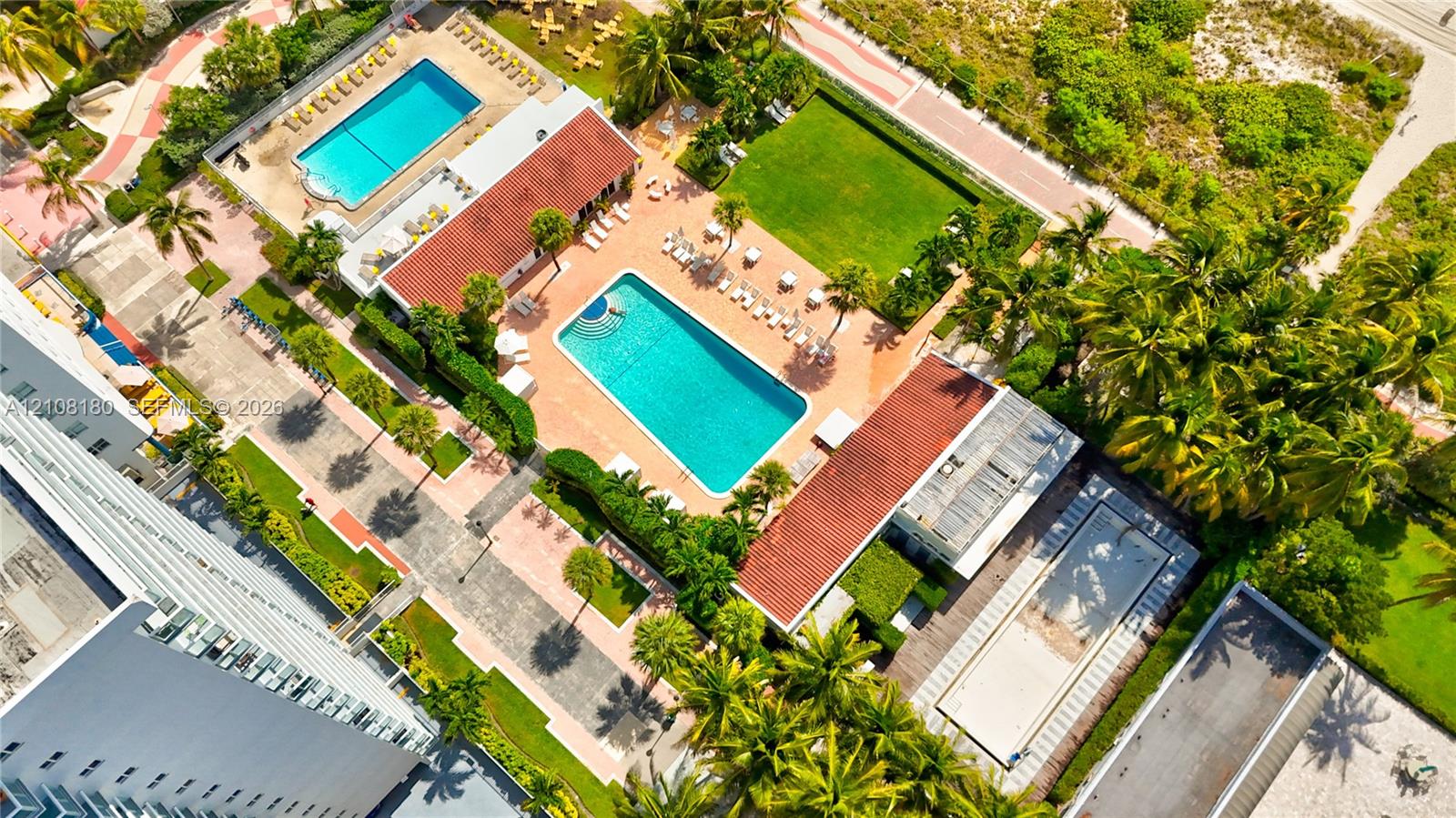 Aerial perspective of the grounds featuring two outdoor swimming pools, manicured lawn space, paved walkways, and mature palm trees Aerial perspective of the grounds featuring two outdoor swimming pools, manicured lawn space, paved walkways, and mature palm trees