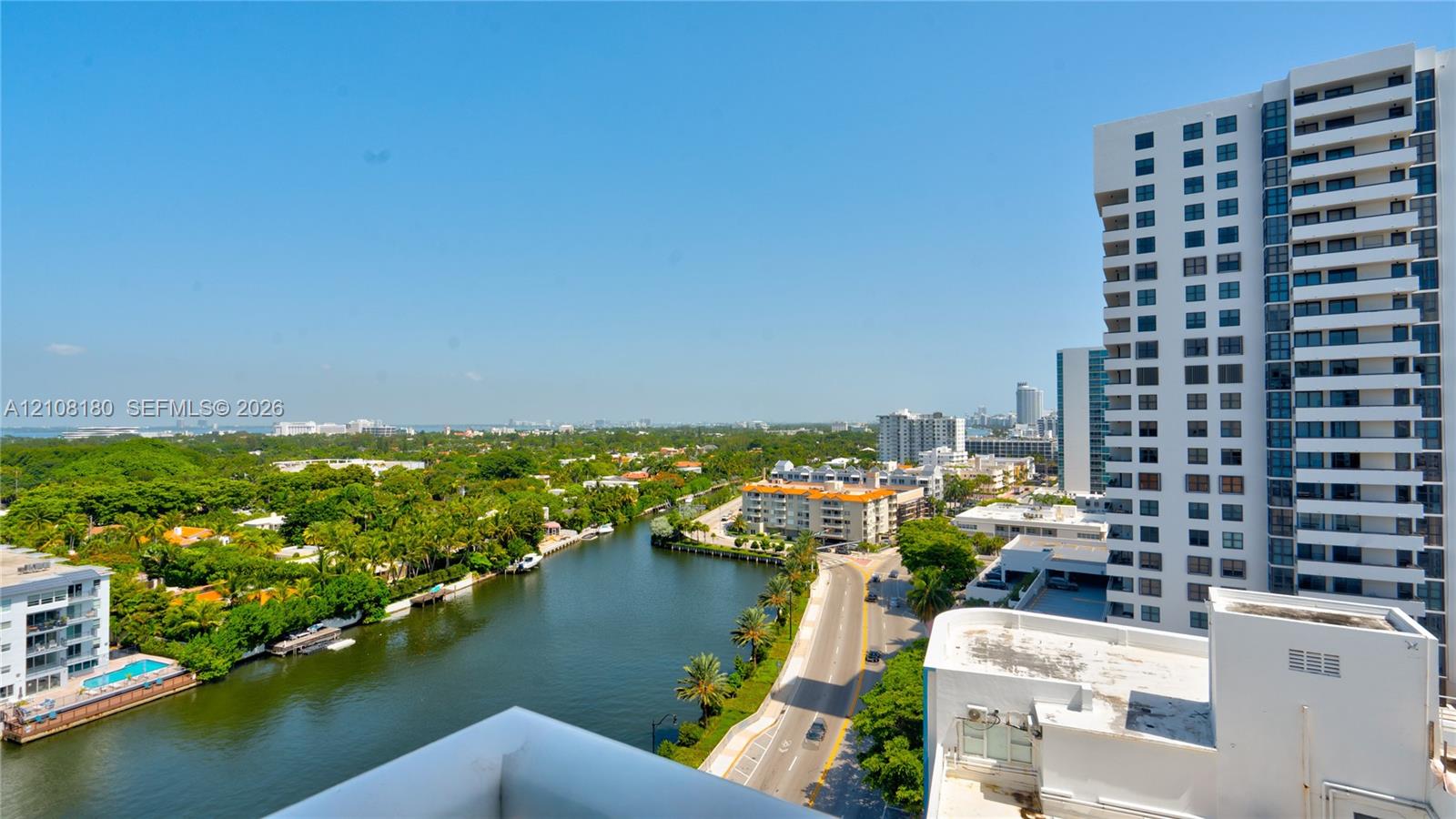 Elevated exterior vantage point featuring panoramic urban scenery, waterway, mature canopy trees, and high-rise architecture
