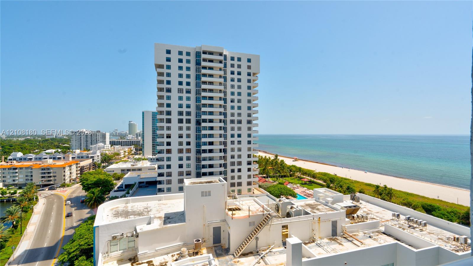 High-rise residential exterior with private balconies, featuring a coastal location with direct access to sandy beaches and open water