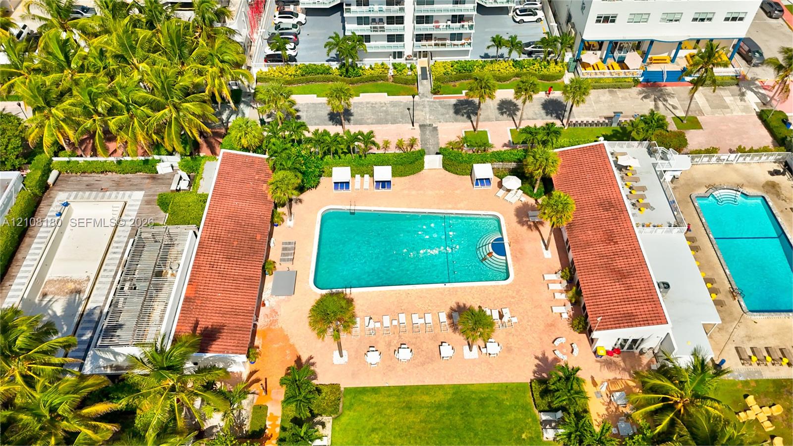 Aerial perspective of a multi-pool courtyard featuring terracotta-tiled roofs, manicured lawns, mature palm trees, and paved deck surfaces Aerial perspective of a multi-pool courtyard featuring terracotta-tiled roofs, manicured lawns, mature palm trees, and paved deck surfaces