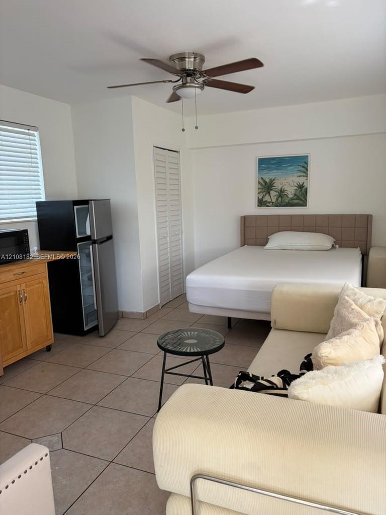 Room featuring ceramic tile flooring, built-in wooden cabinetry, louvered closet doors, and a ceiling fan Room featuring ceramic tile flooring, built-in wooden cabinetry, louvered closet doors, and a ceiling fan