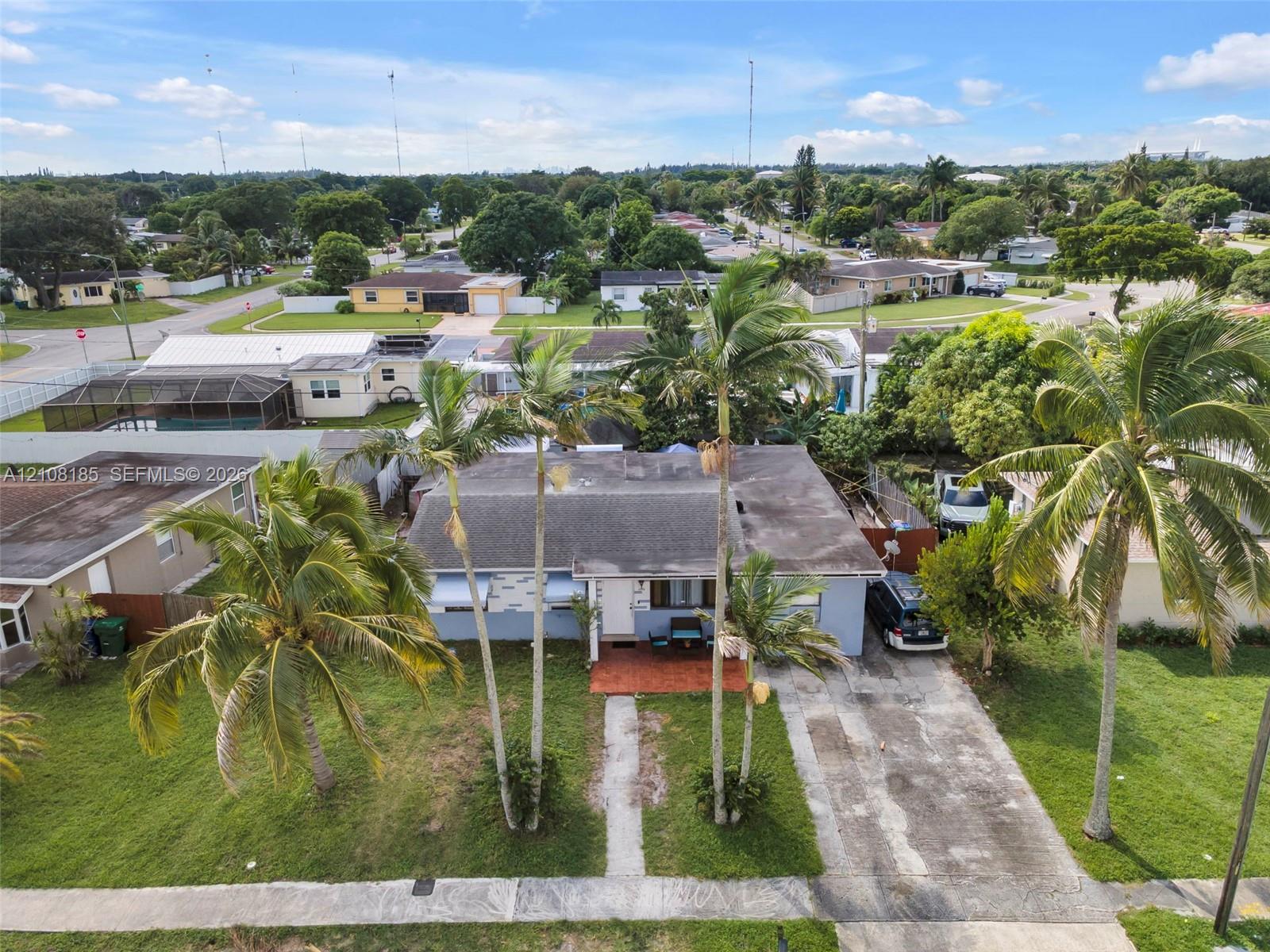 Single-story residence featuring a concrete driveway, a covered front entryway, and mature palm trees