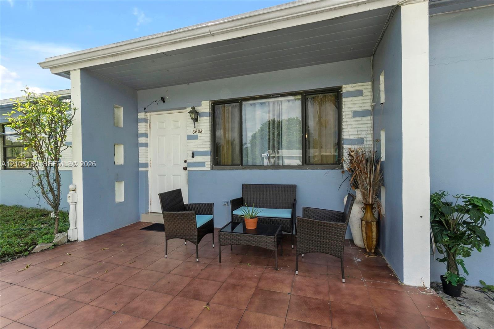 Covered porch featuring a tiled surface, painted stucco exterior, decorative recessed wall niches, and a multi-pane front window