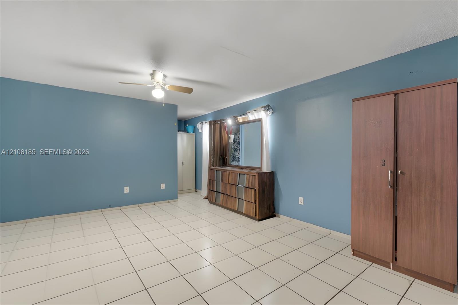 Neutral-toned tile flooring, ceiling-mounted fan with light fixture, and light-filled interior space