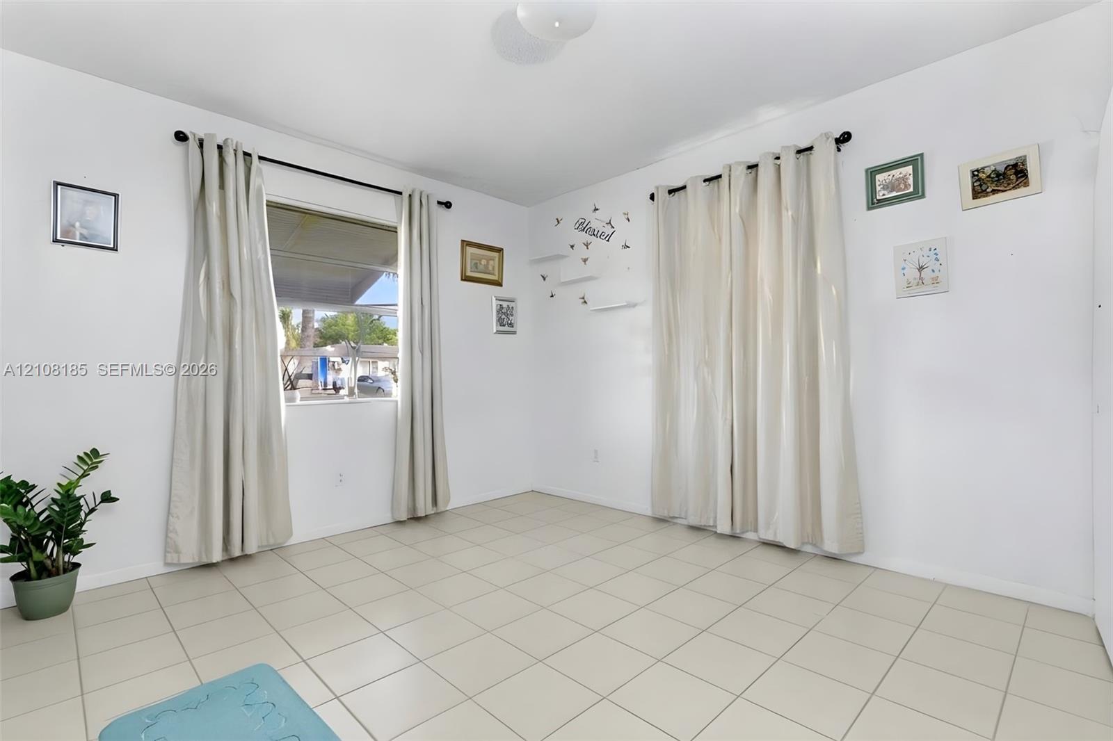 Room featuring neutral tile flooring, dual windows with wall-mounted rods, and overhead flush-mount lighting
