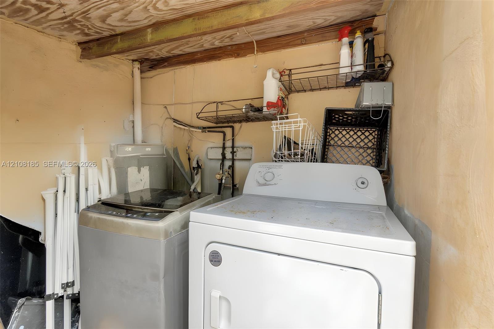 Laundry area featuring concrete block walls, exposed wood ceiling joists, and integrated wall-mounted wire shelving
