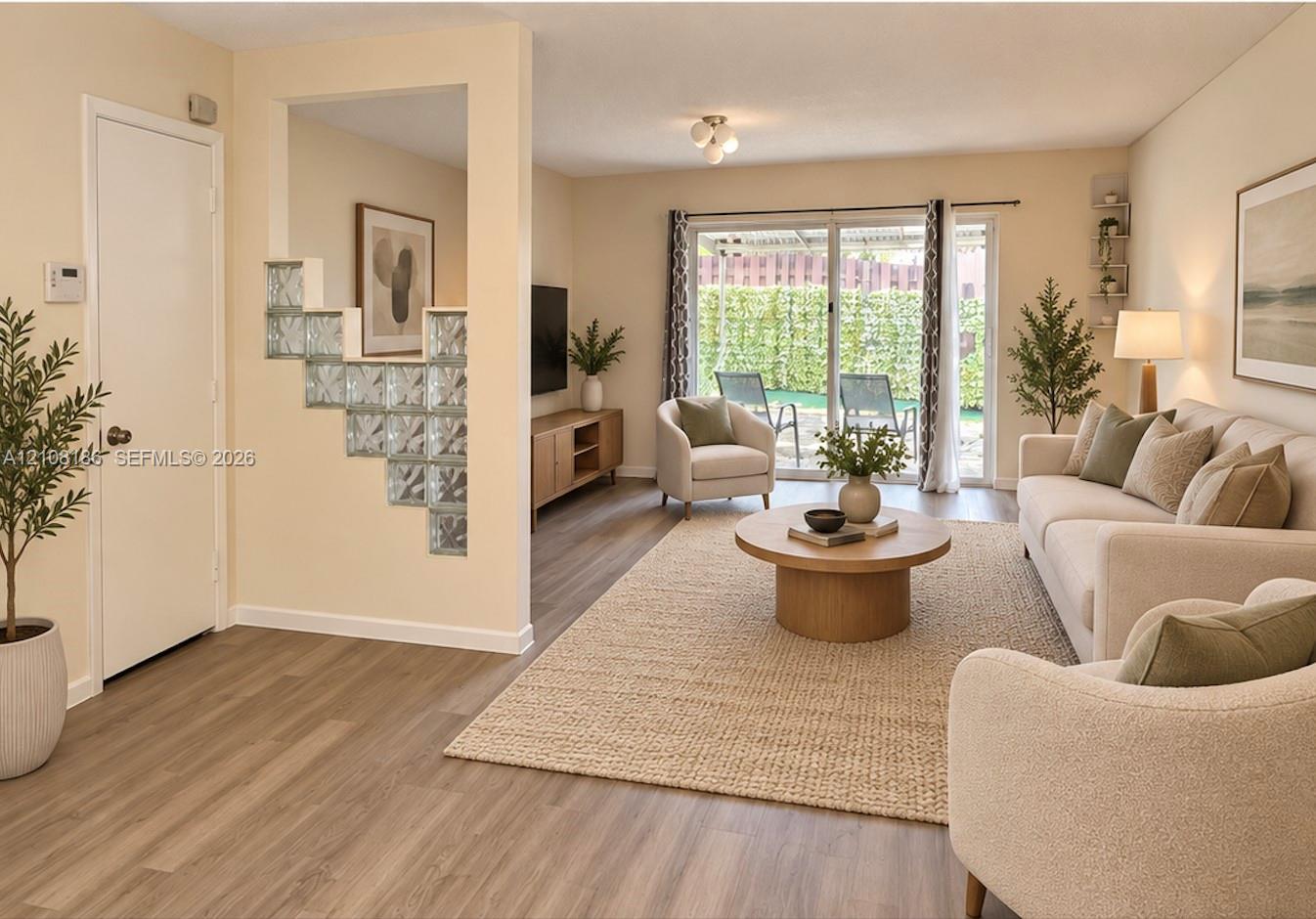 Living area featuring wood-finish flooring, a decorative glass block partition, and sliding glass doors providing outdoor access