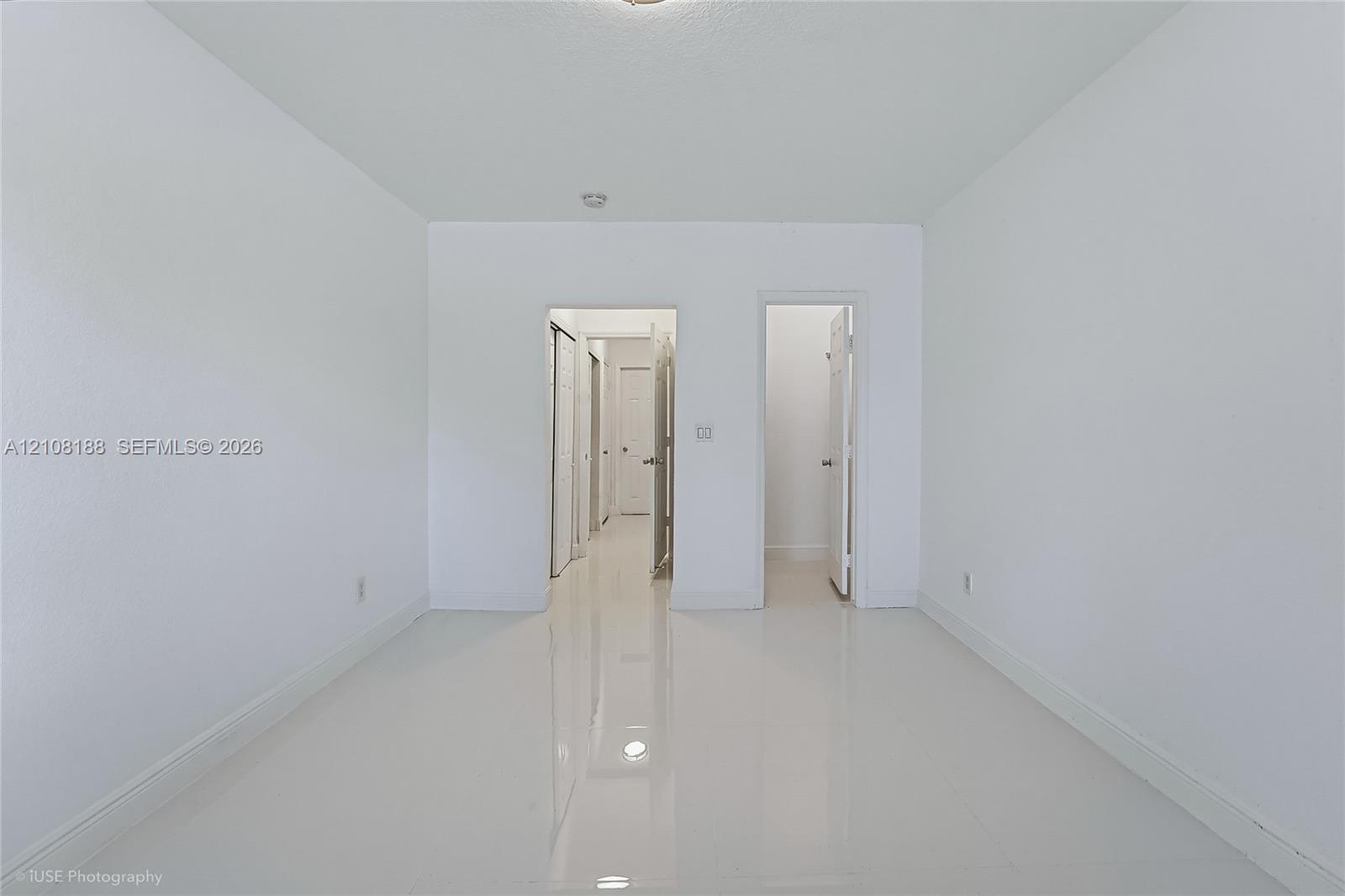 Neutral interior featuring high-gloss tile flooring, smooth wall finishes, and multiple closet access points