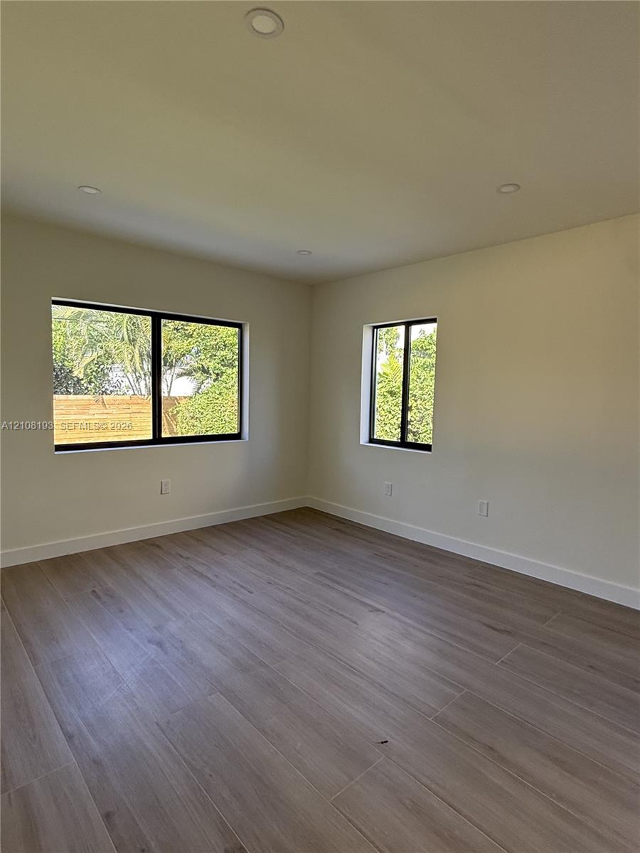 Interior space featuring wood-finish flooring, recessed lighting, and windows with black frames