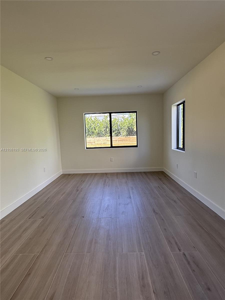 Neutral interior featuring wood-finish flooring, recessed lighting, and windows with black frames