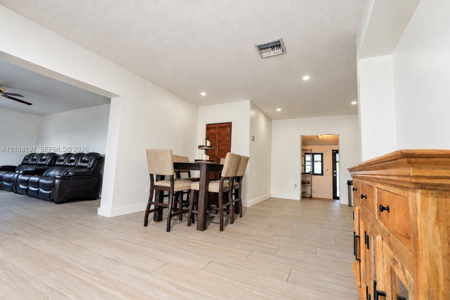 Open-concept interior featuring light wood-finish flooring, recessed lighting, and a neutral color palette