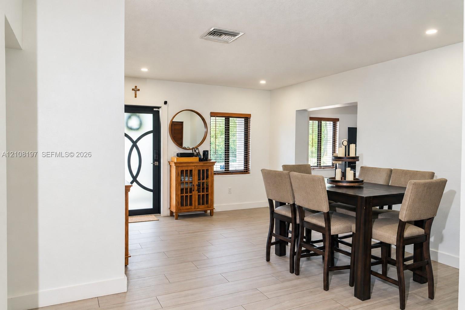 Neutral-toned tile flooring, recessed ceiling lighting, and a front entry door featuring circular geometric glass detailing