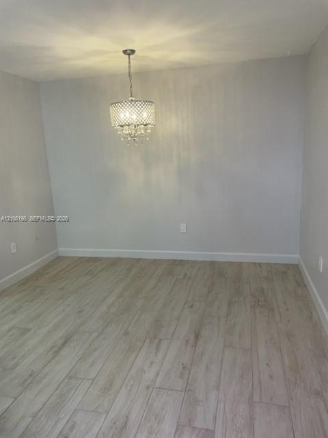 Neutral-toned interior room featuring wood-finish flooring and a drum-style crystal chandelier