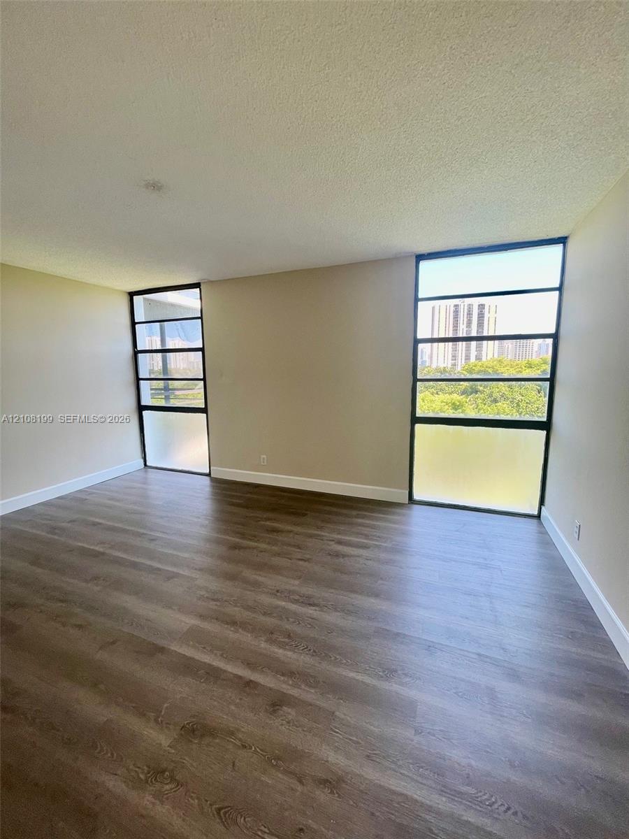 Living area featuring wood-finish flooring and floor-to-ceiling multi-pane windows with frosted glass lower panels Living area featuring wood-finish flooring and floor-to-ceiling multi-pane windows with frosted glass lower panels