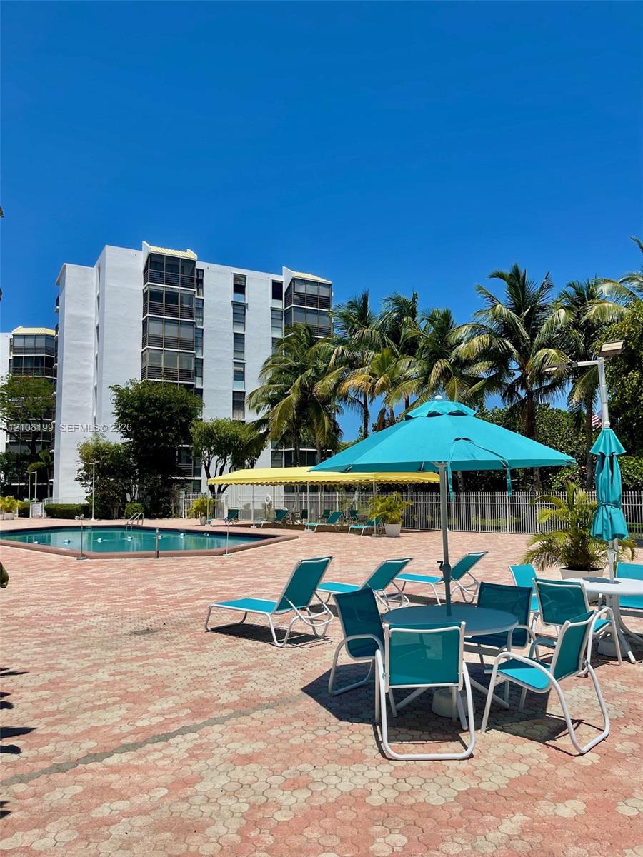 Swimming pool with a paved deck, perimeter fencing, and mature palm trees