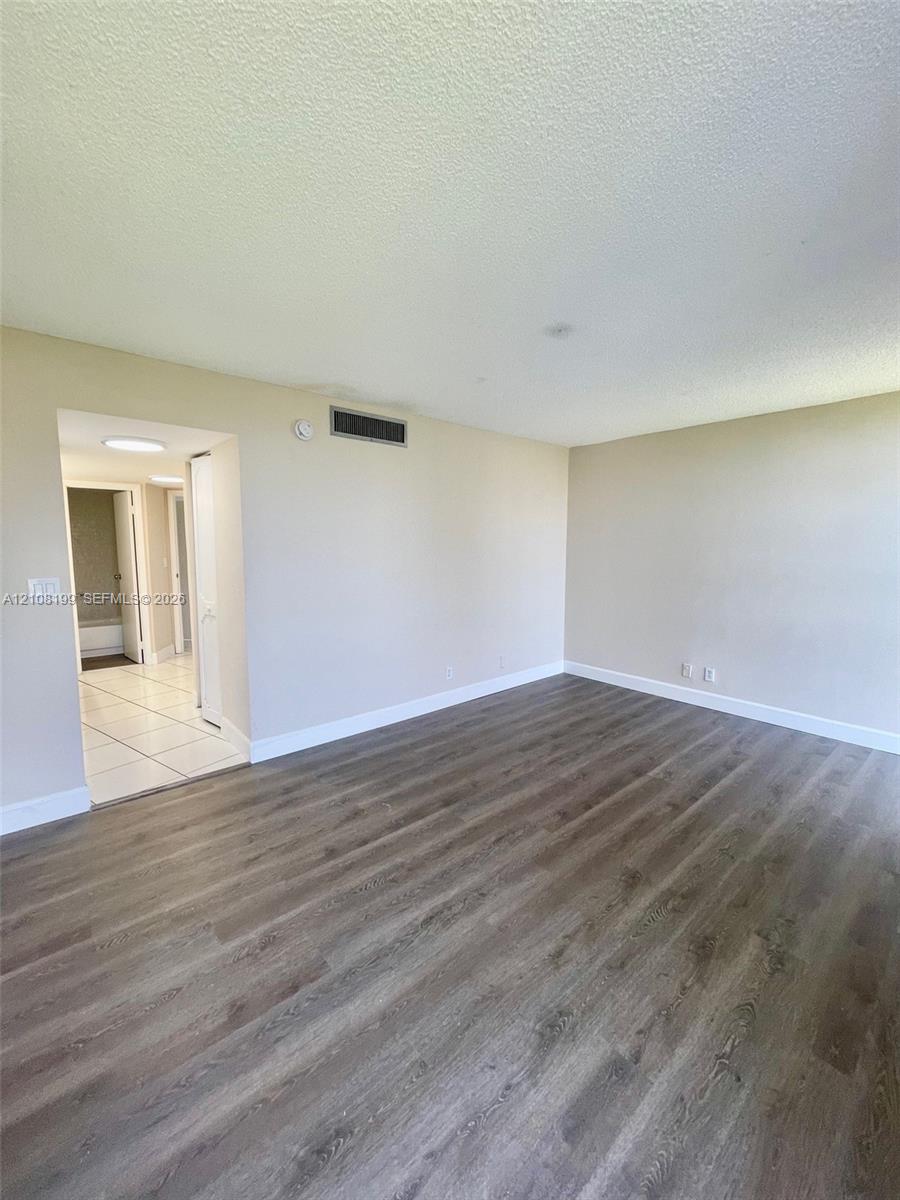 Neutral-toned interior space featuring wood-finish flooring and tile flooring in the secondary area