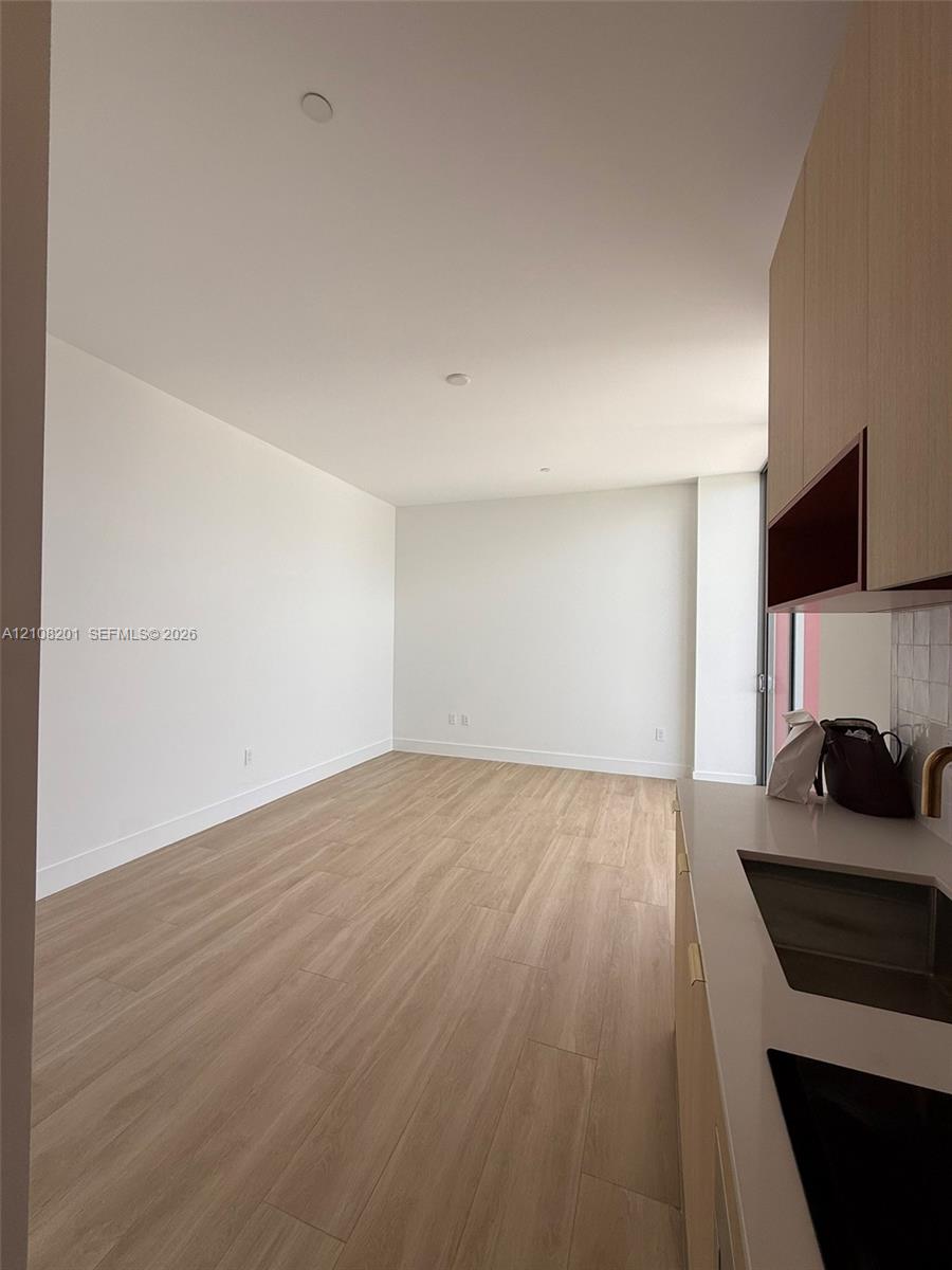 Wood-finish flooring, light-toned cabinetry, solid-surface countertop, undermount sink, and recessed lighting