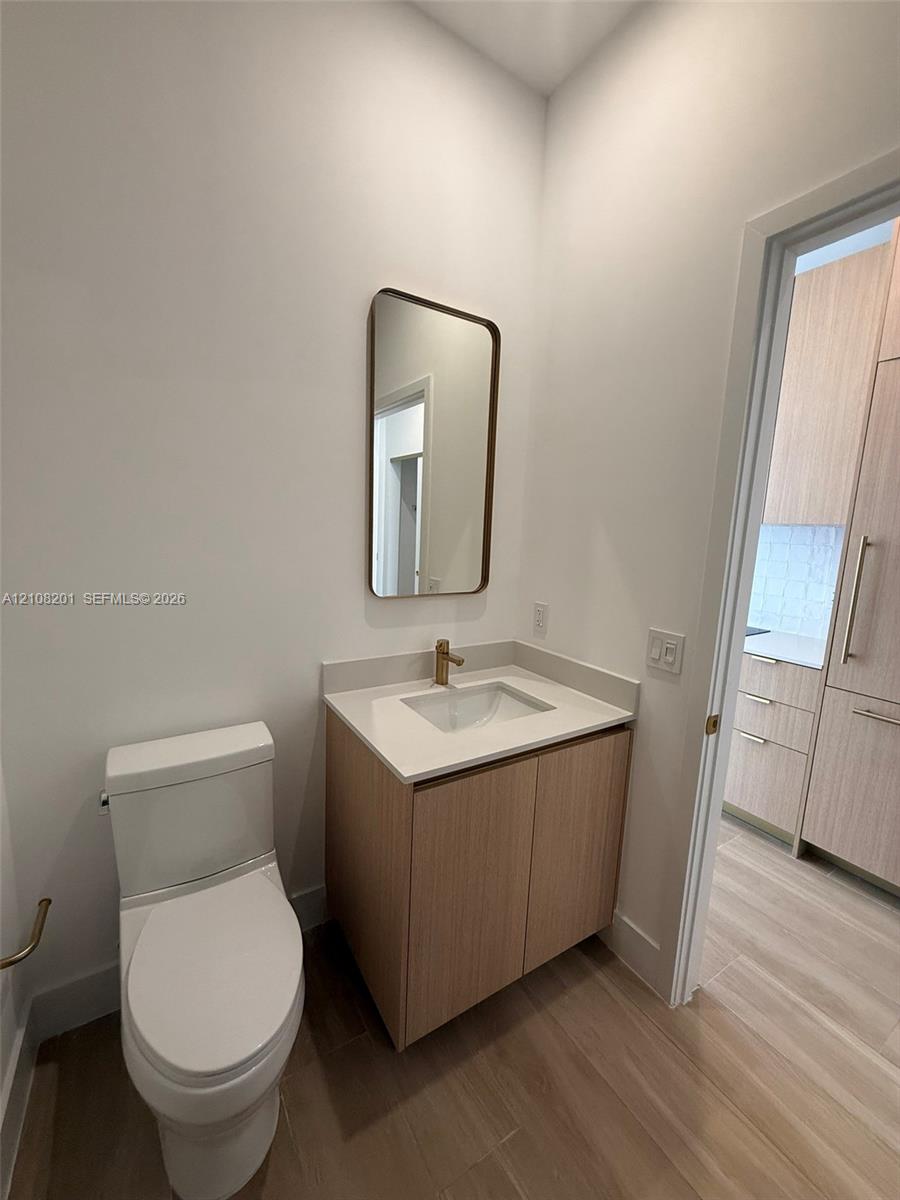 Modern floating vanity with a neutral-tone countertop, rectangular undermount sink, brass-finish faucet, and coordinating wall-mounted mirror Modern floating vanity with a neutral-tone countertop, rectangular undermount sink, brass-finish faucet, and coordinating wall-mounted mirror
