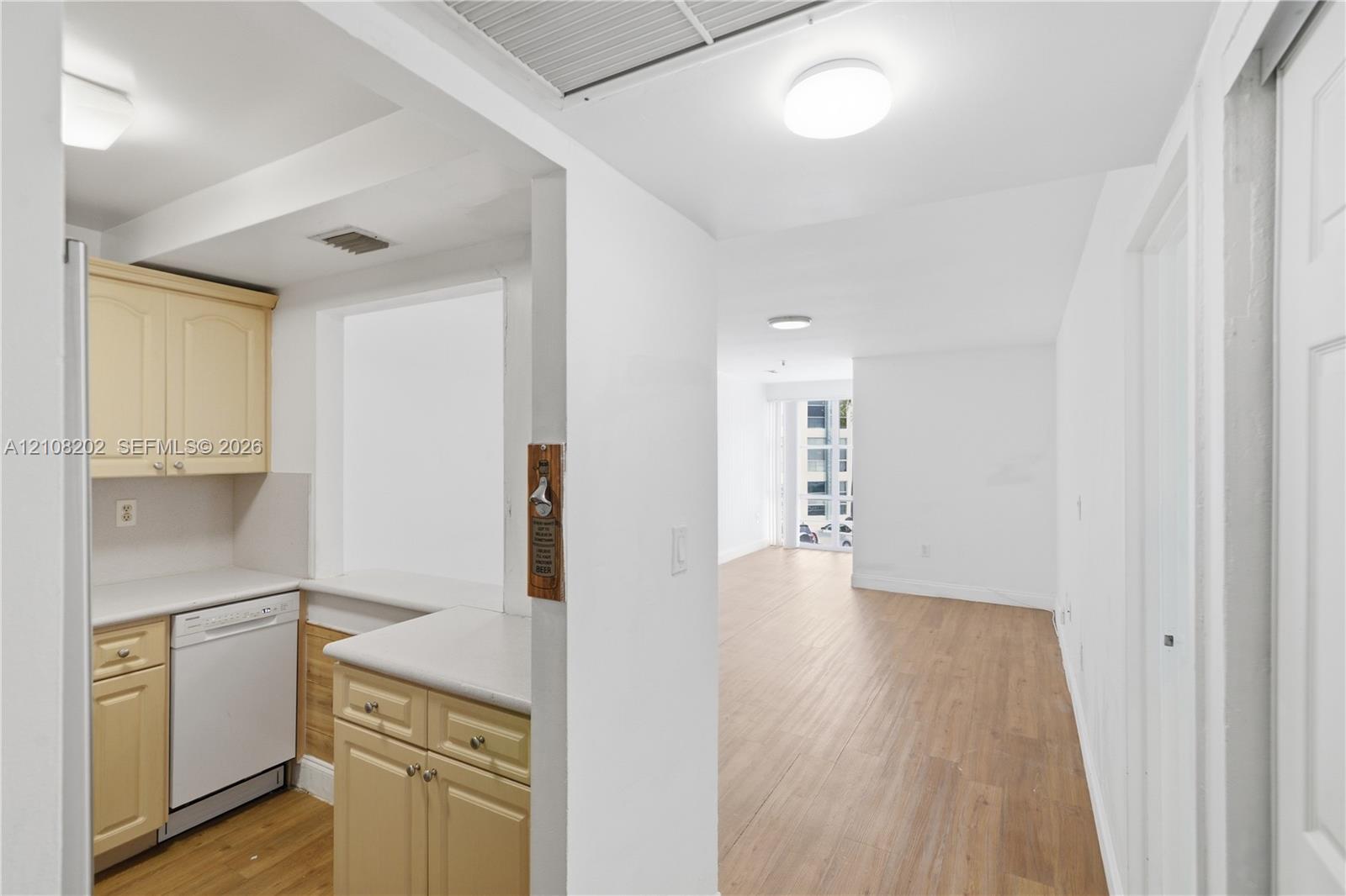 Kitchen featuring wood-finish cabinetry, solid surface countertops, a built-in dishwasher, and wood-finish flooring Kitchen featuring wood-finish cabinetry, solid surface countertops, a built-in dishwasher, and wood-finish flooring