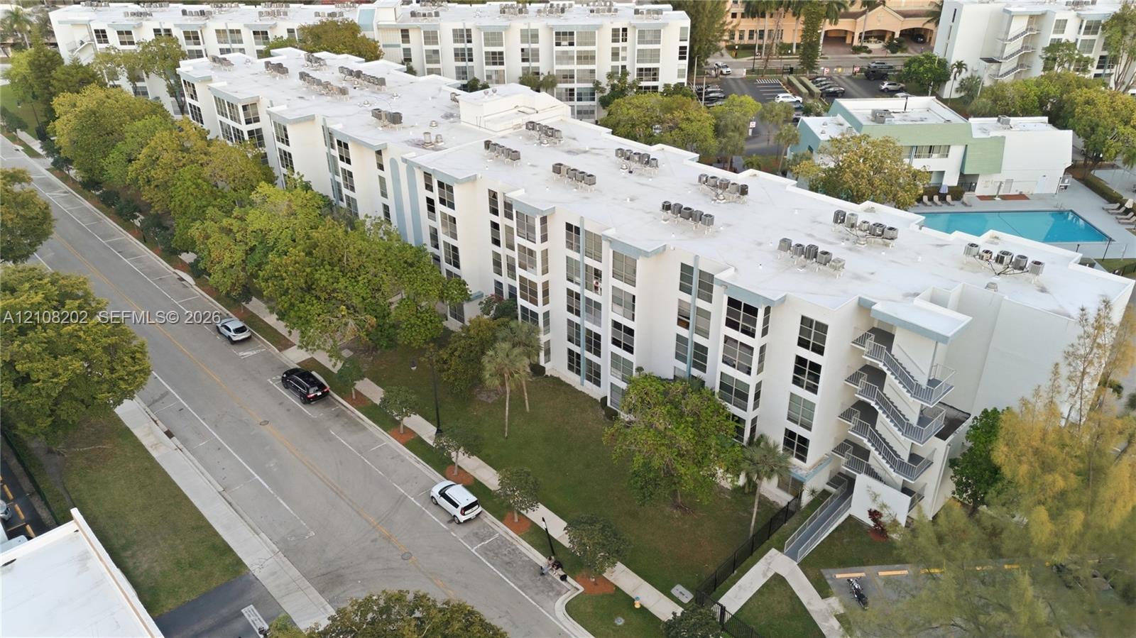 Multi-story building exterior featuring a white facade, structured metal stairwells, flat roofing, and an onsite swimming pool Multi-story building exterior featuring a white facade, structured metal stairwells, flat roofing, and an onsite swimming pool