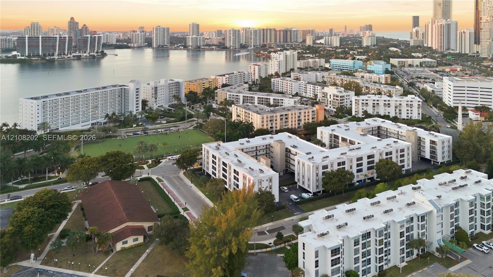 Aerial perspective of mid-rise multi-family residential structures situated in an urban coastal setting with mature landscaping