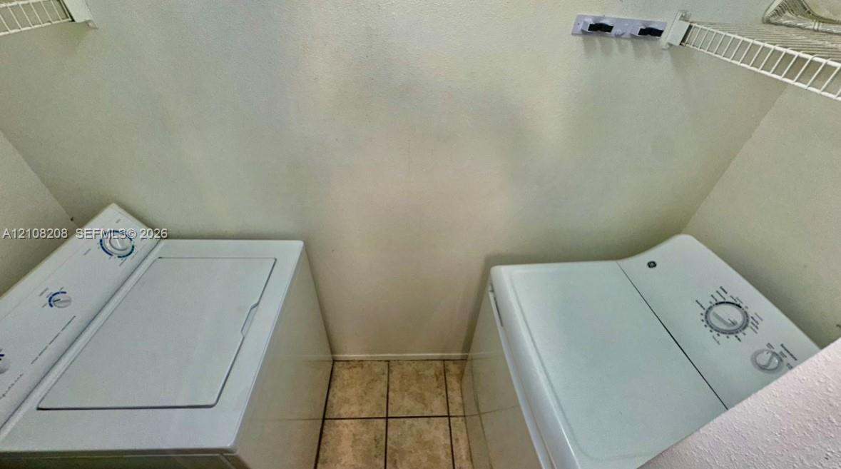 Laundry area featuring ceramic tile flooring, wire shelving, and built-in wall hardware