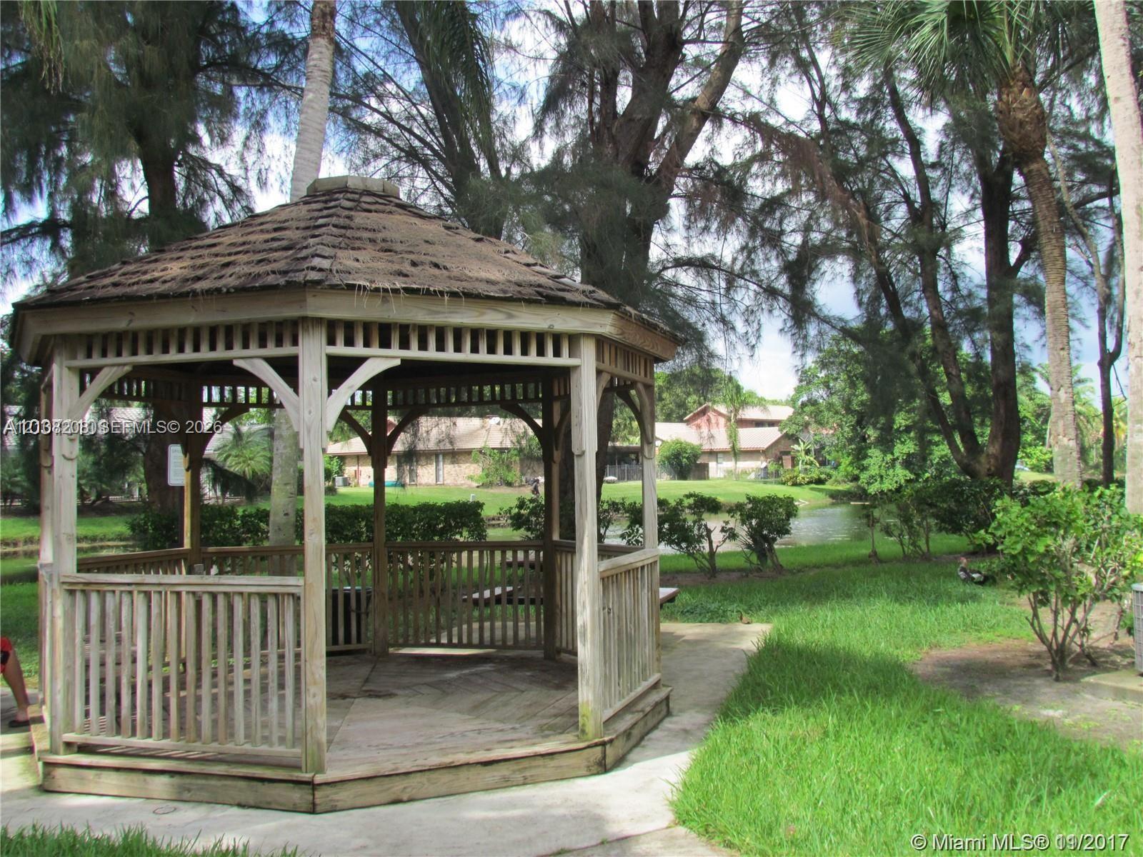 Octagonal wood gazebo featuring shingle roofing, lattice detailing, and a raised wooden deck