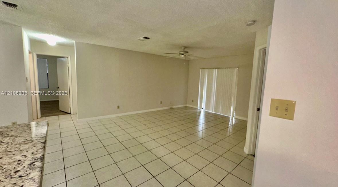 Open floor plan featuring tile flooring, ceiling fan, and sliding glass patio doors
