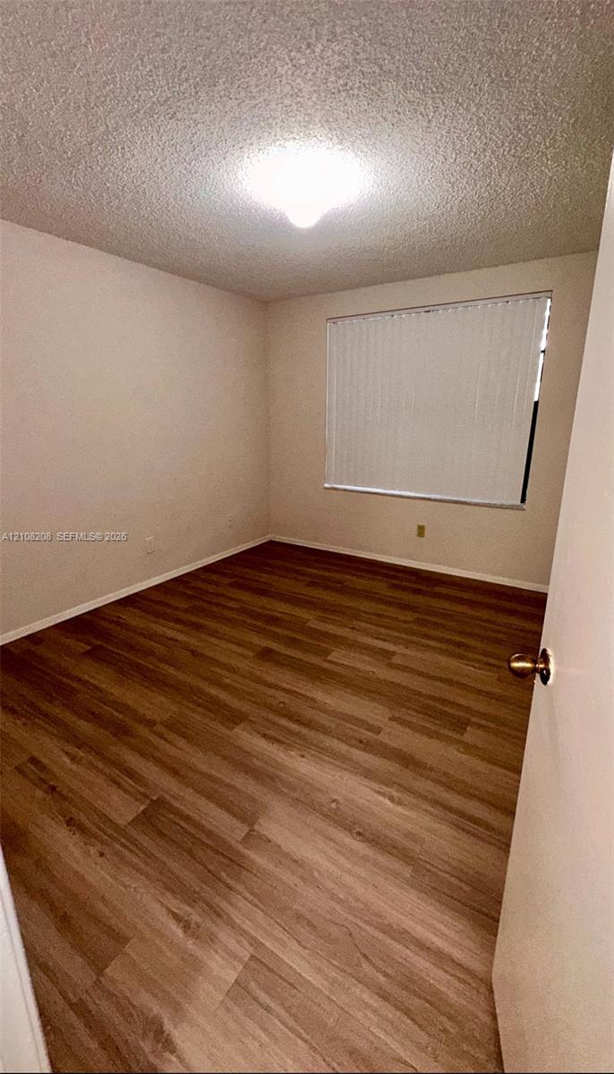 Room featuring wood-finish flooring, textured ceiling, flush-mount lighting, and window blinds
