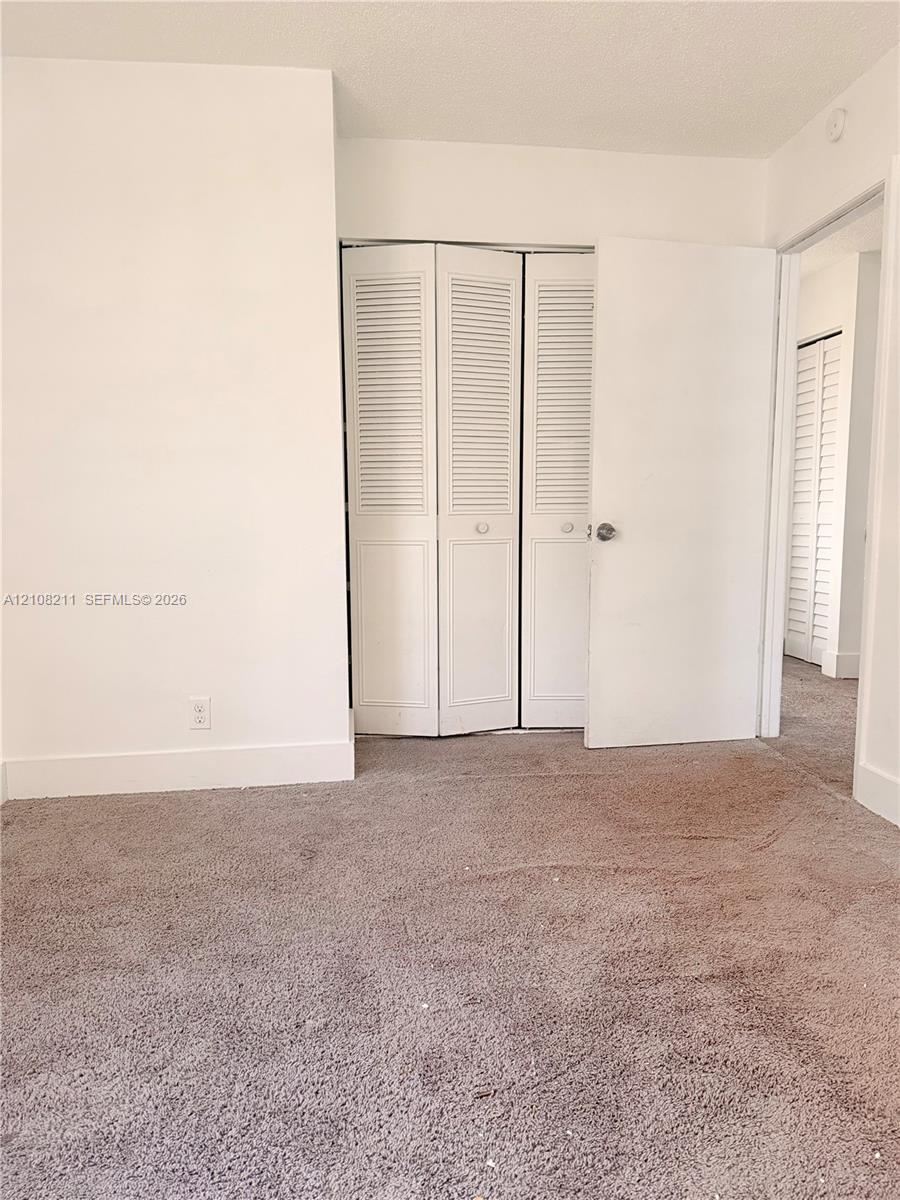 Neutral-toned carpeting and white interior doors featuring louvered panels
