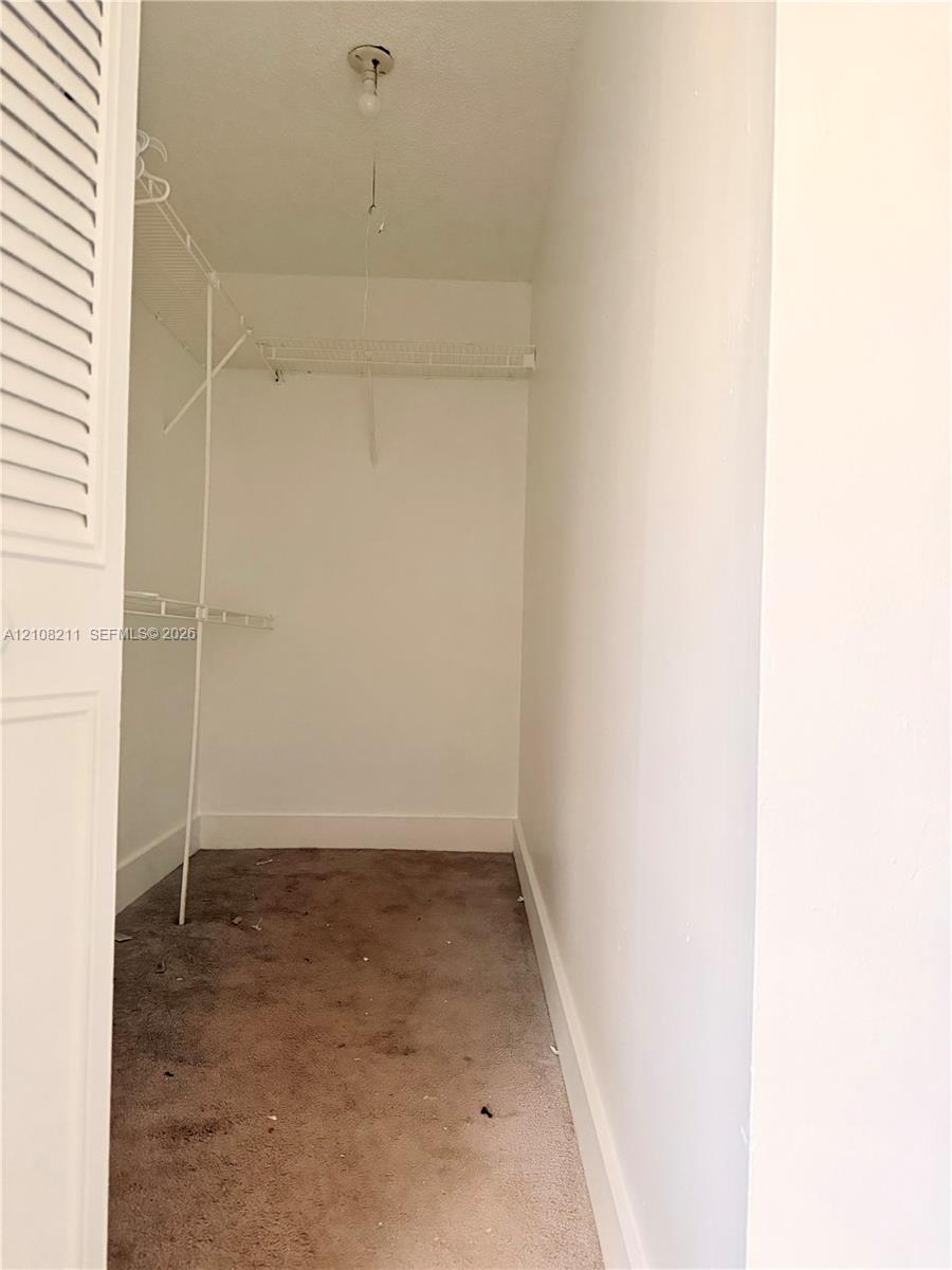 Storage closet featuring white-painted walls, carpeting, ceiling-mounted light fixture, and wire shelving system