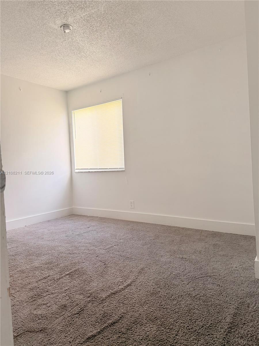 Room interior featuring neutral-toned carpeting, white walls, and a single window with installed blinds