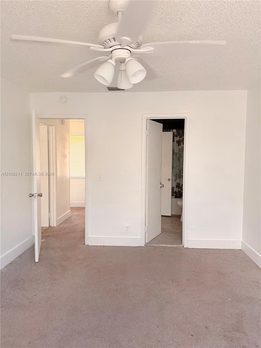 Neutral-toned wall-to-wall carpeting and a white multi-blade ceiling fan with integrated three-light fixture