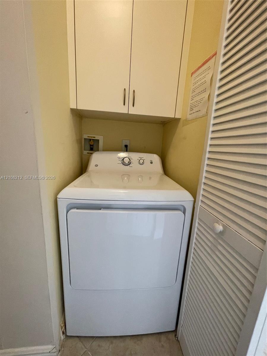 Built-in upper storage cabinetry, louvered closet door, and designated utility hookups