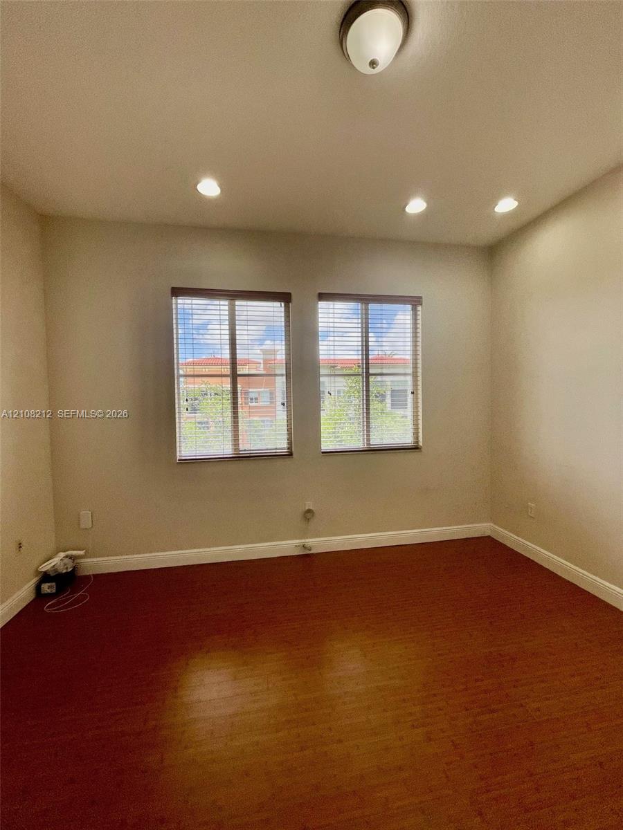 Interior room featuring wood-finish flooring, dual windows with blinds, recessed lighting, and a flush-mount ceiling fixture