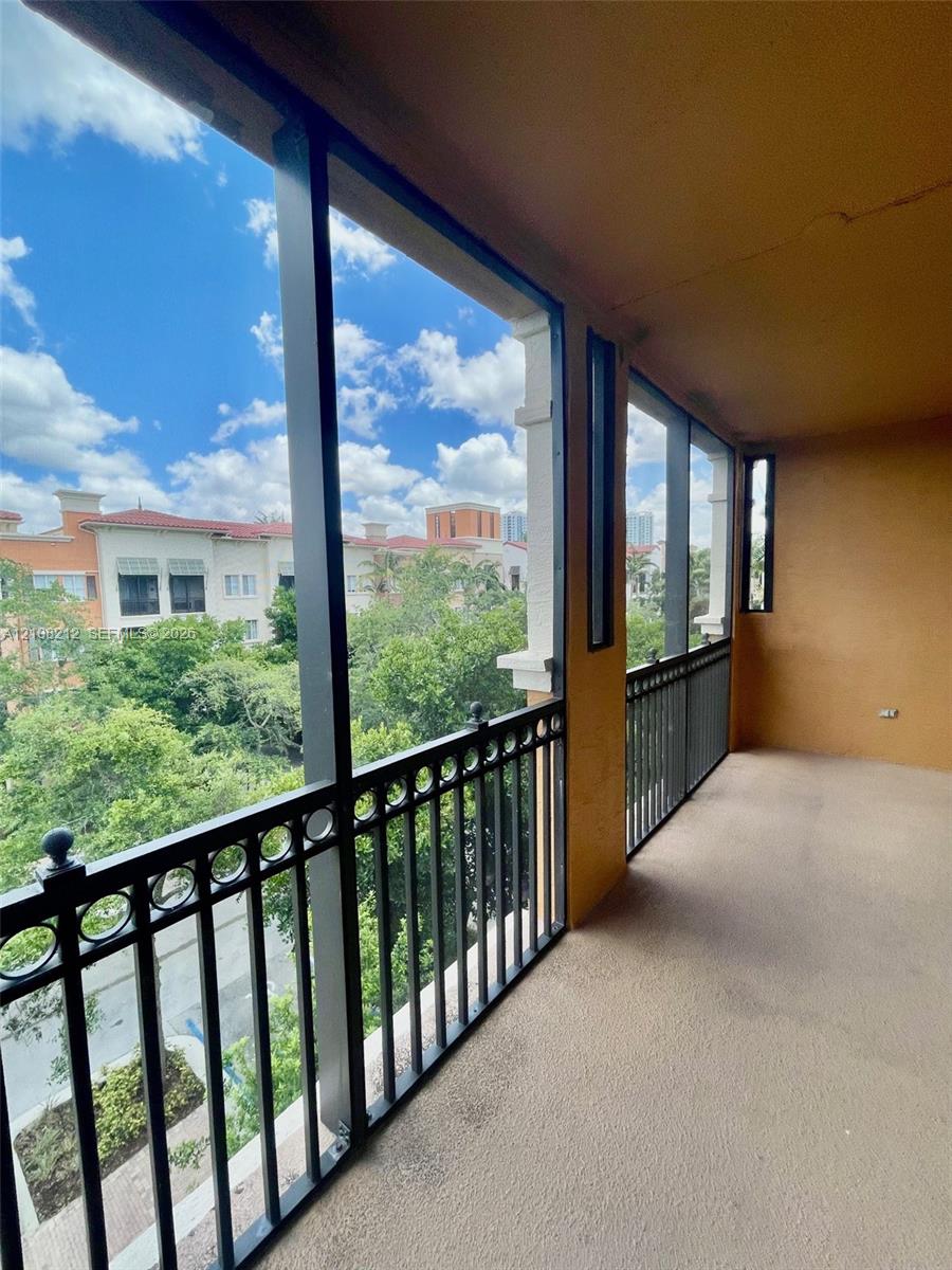 Covered balcony featuring screen enclosures, decorative metal railings, and concrete flooring