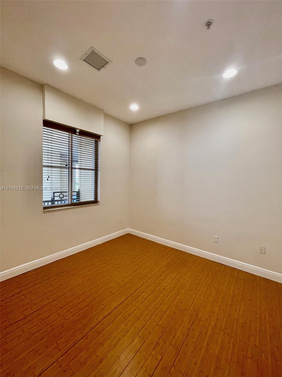 Room featuring wood-finish flooring, recessed lighting, and a window with horizontal blinds