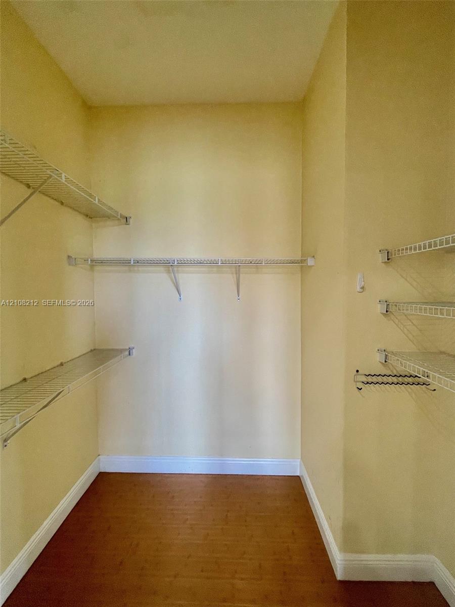 Walk-in storage space featuring wood-finish flooring and multiple tiers of wire shelving