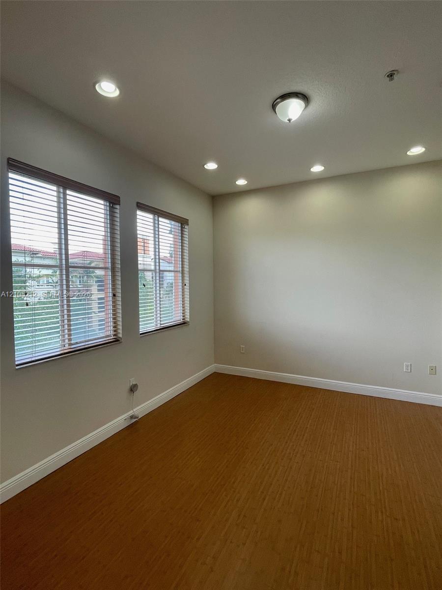 Room featuring wood-finish flooring, recessed lighting, neutral wall paint, and dual windows equipped with horizontal blinds