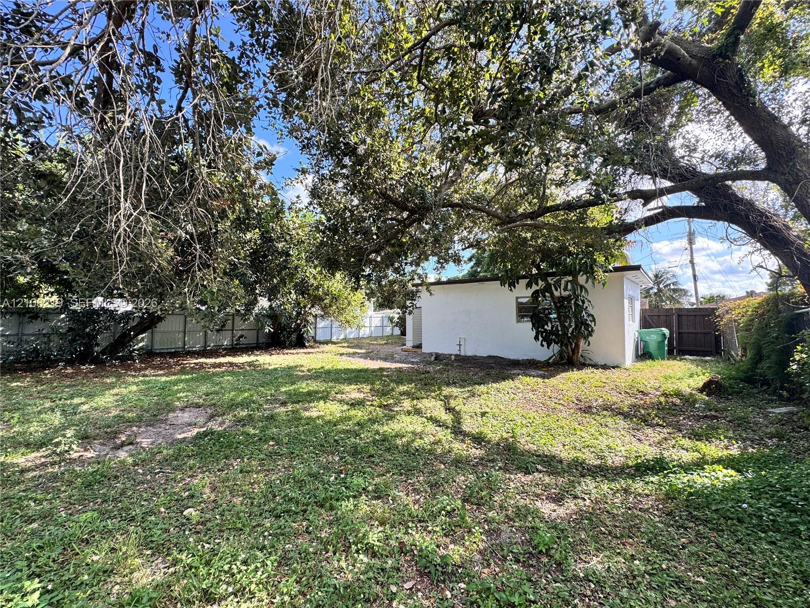 Backyard featuring a grass lawn, mature trees, and perimeter fencing