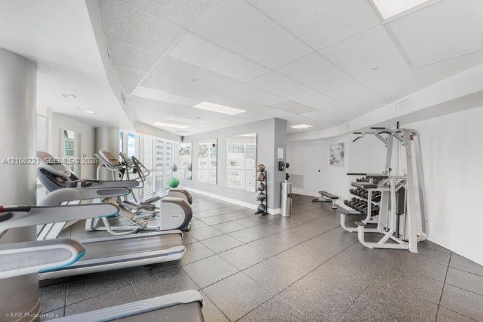 Fitness center featuring square tile flooring, recessed lighting, and wall-mounted mirrors