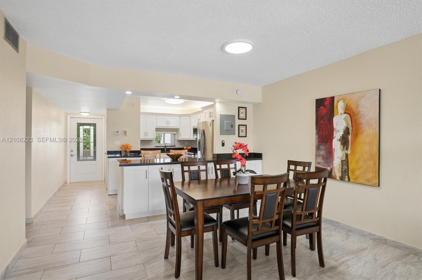 Kitchen featuring white cabinetry, dark countertops, tile flooring, and a glass-paneled exterior entry door