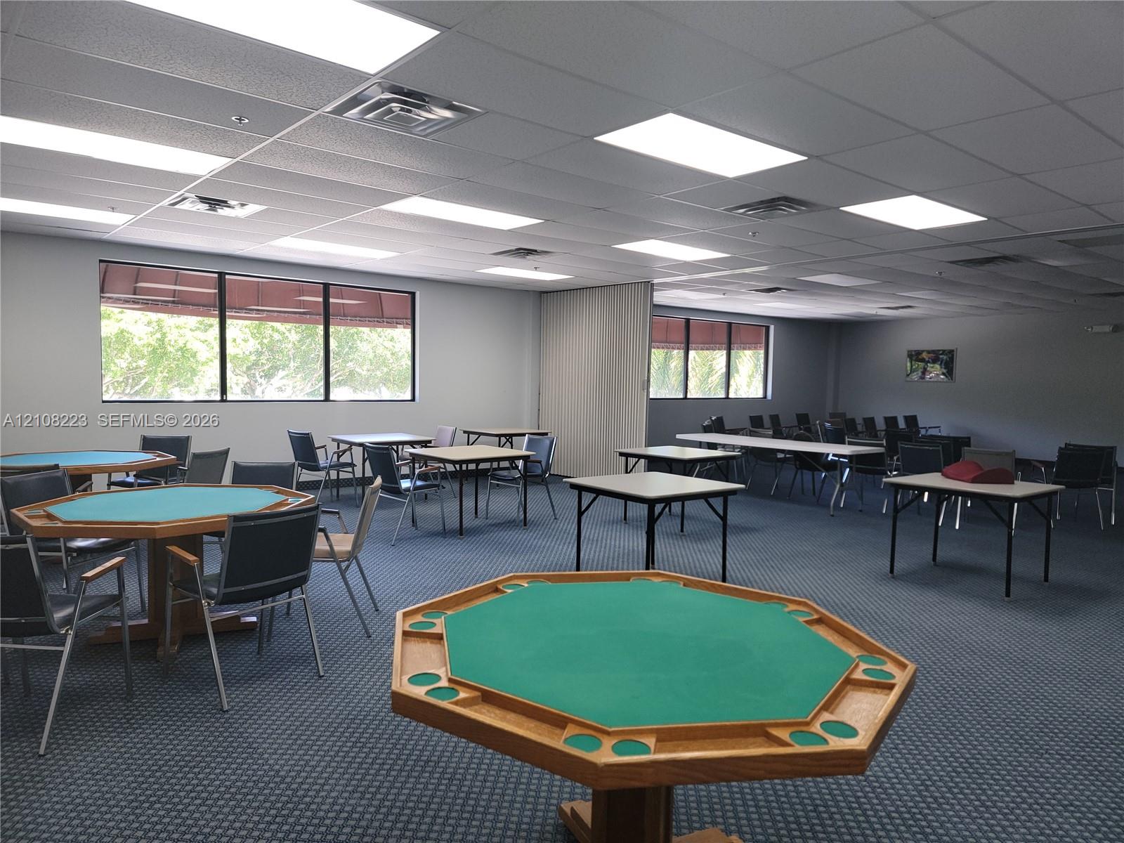 Expansive multipurpose room featuring a drop ceiling with recessed lighting, integrated carpet flooring, and large windows