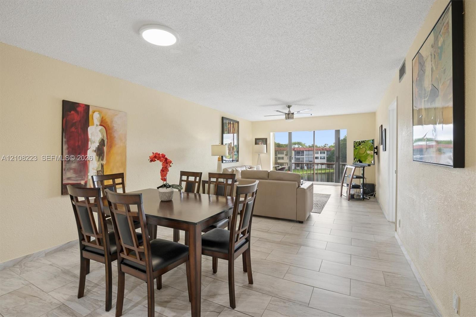 Light-toned tile flooring, ceiling-mounted fan, and floor-to-ceiling sliding glass doors