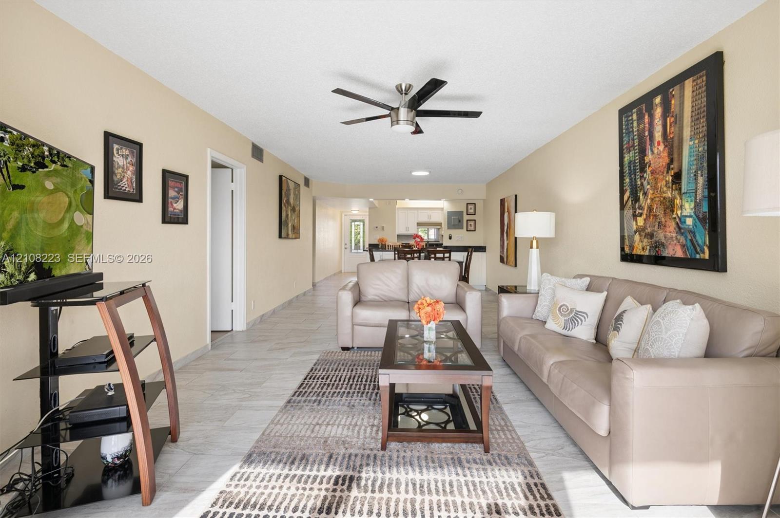Open-concept interior featuring light-toned tile flooring and a ceiling-mounted fan with integrated lighting