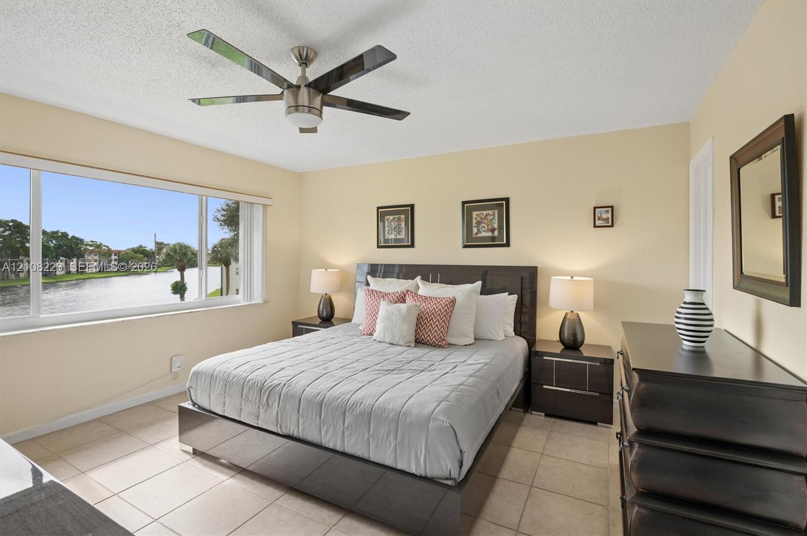 Large window with water scenery, tile flooring, and a ceiling fan with integrated lighting