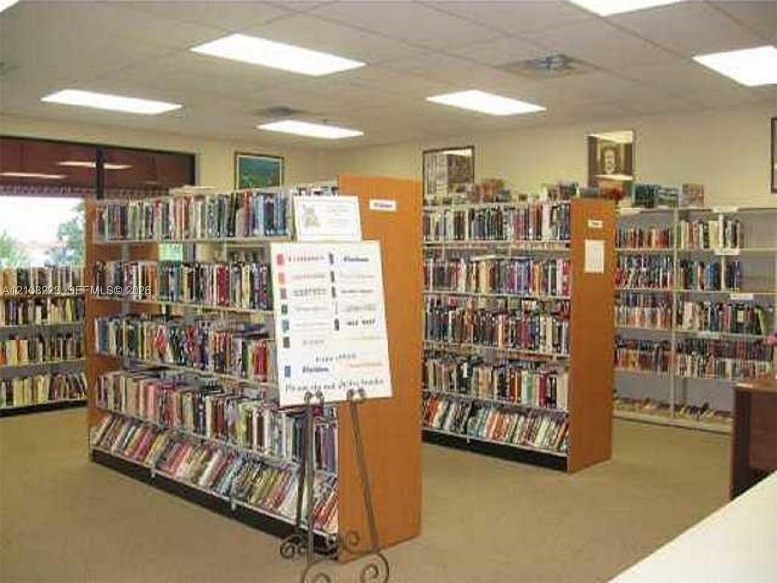Spacious room featuring neutral carpeting, recessed ceiling lighting, and multiple rows of built-in shelving units