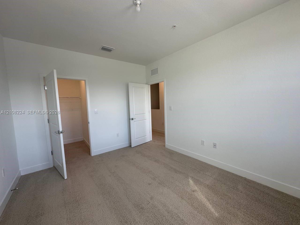 Neutral-toned wall-to-wall carpeting, two interior panel doors, and built-in closet shelving