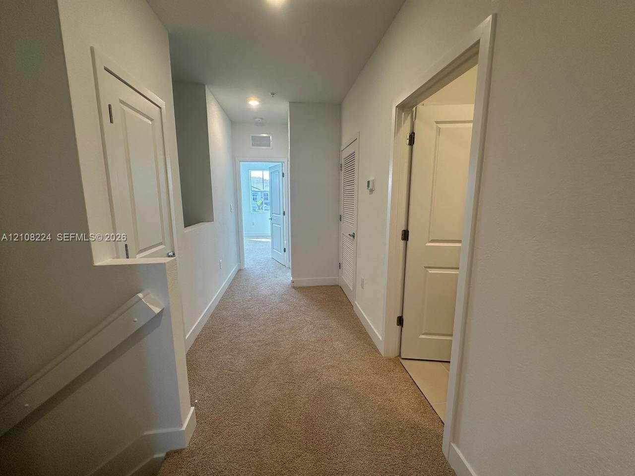 Neutral-toned carpeting, multi-panel interior doors, and recessed ceiling lighting